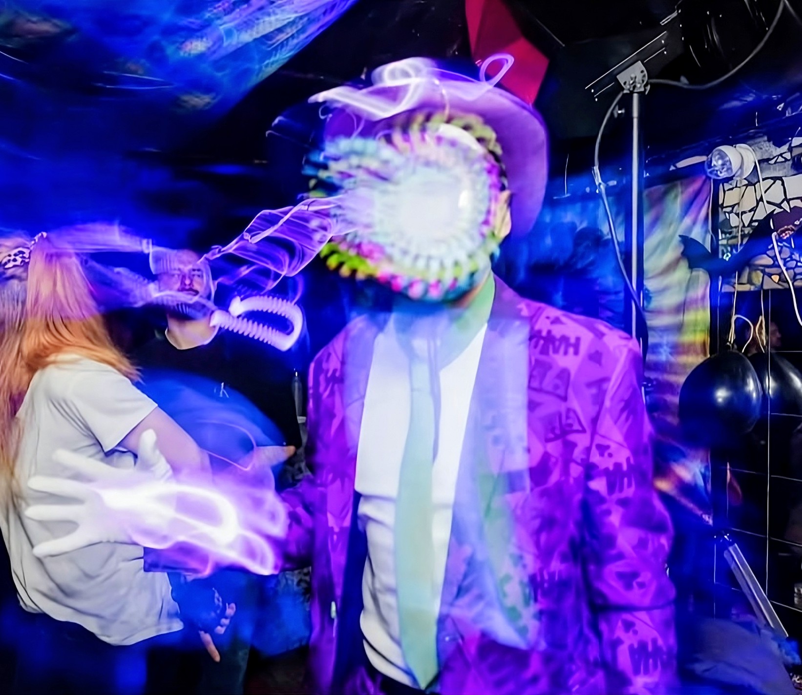 Psyderman live on the floor — LED mask glowing through long-exposure light trails